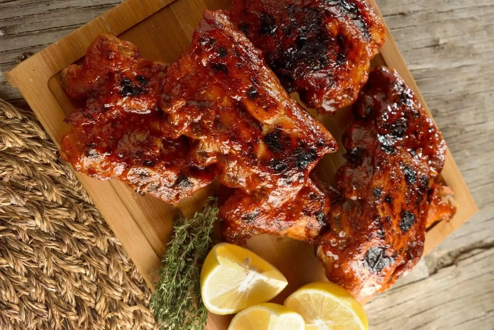 Costillitas de cerdo en salsa BBQ servidas con limón
